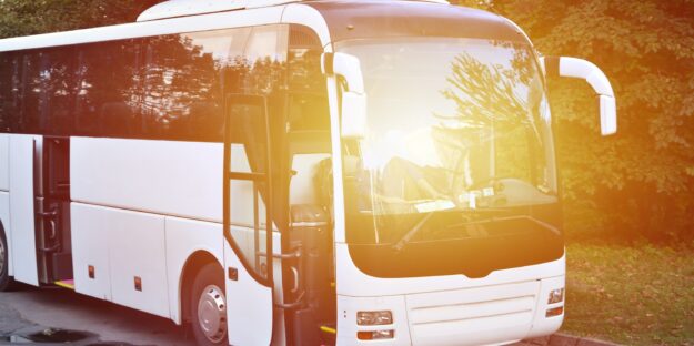 White tourist bus for excursions. The bus is parked in a parking lot near the park